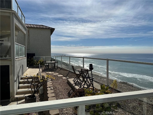 balcony featuring a view of the beach and a water view