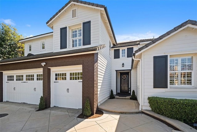 traditional-style home with an attached garage, concrete driveway, and brick siding