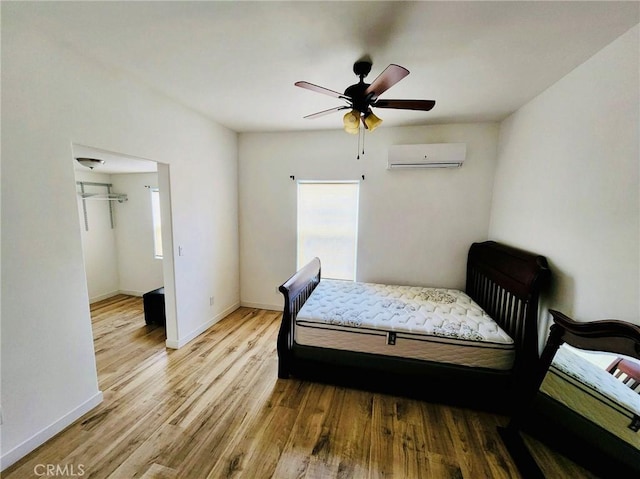 bedroom with an AC wall unit, ceiling fan, and light wood-type flooring