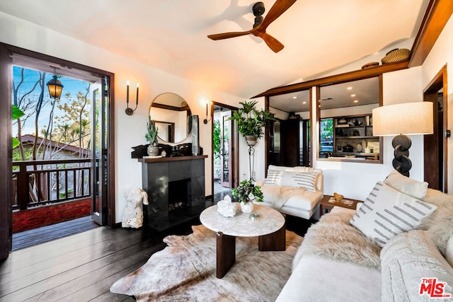 living room with hardwood / wood-style flooring, ceiling fan, lofted ceiling, and a tiled fireplace