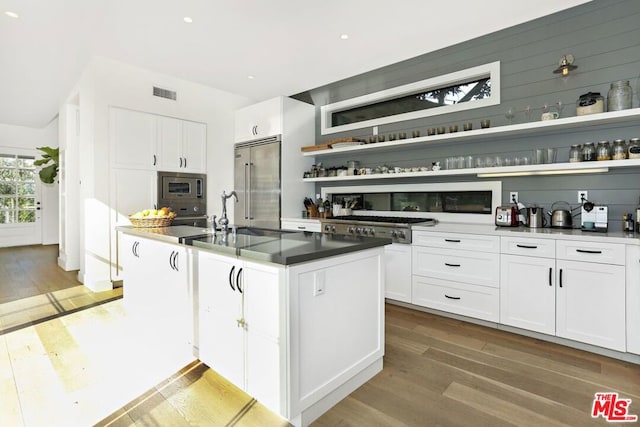 kitchen featuring white cabinetry, built in appliances, and hardwood / wood-style flooring