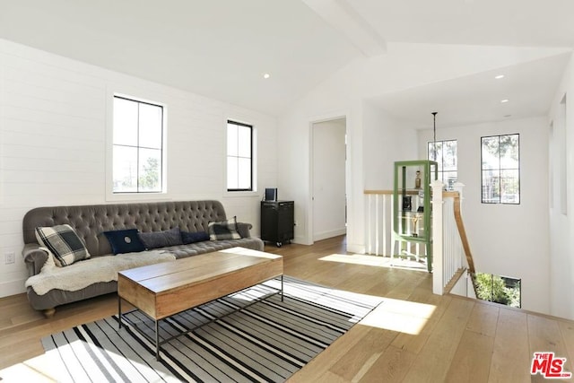 living room featuring vaulted ceiling with beams and light hardwood / wood-style flooring