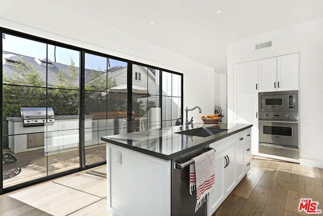 kitchen featuring an island with sink, appliances with stainless steel finishes, sink, and white cabinets