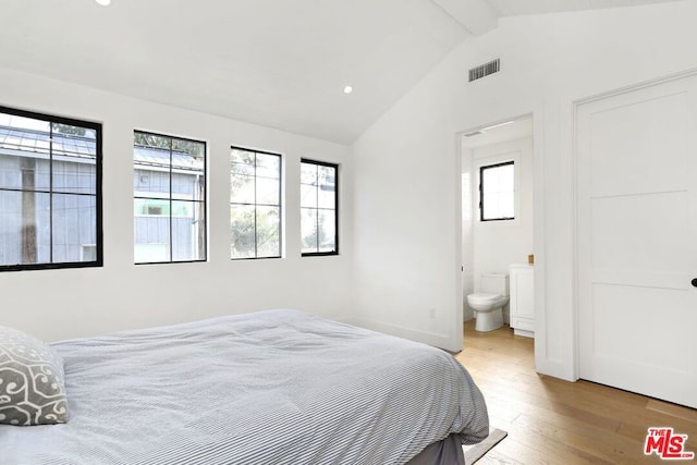 bedroom with lofted ceiling with beams, ensuite bathroom, and light hardwood / wood-style flooring