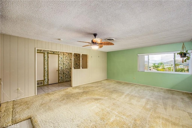 carpeted spare room featuring visible vents, a textured ceiling, and a ceiling fan