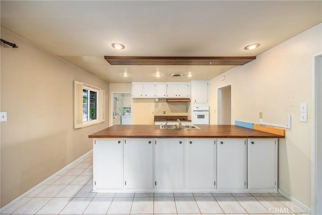 kitchen featuring oven, a sink, washer / clothes dryer, a peninsula, and white cabinets