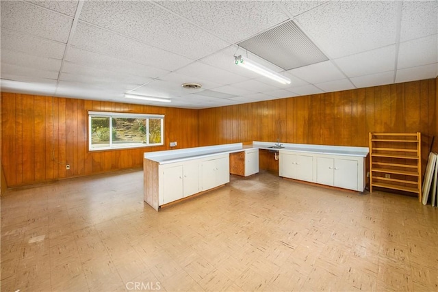 kitchen featuring wooden walls, light floors, light countertops, white cabinets, and built in desk