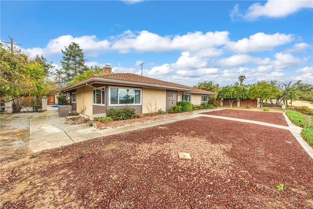 single story home featuring stucco siding, fence, and a chimney