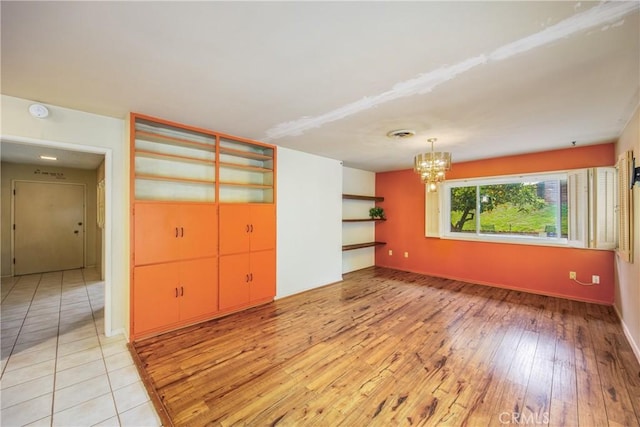 spare room featuring a chandelier, visible vents, and light wood-style floors