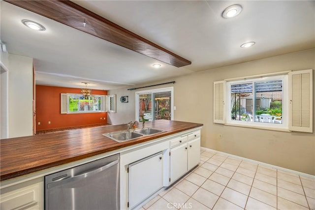 kitchen with stainless steel dishwasher, light tile patterned flooring, wooden counters, and a sink