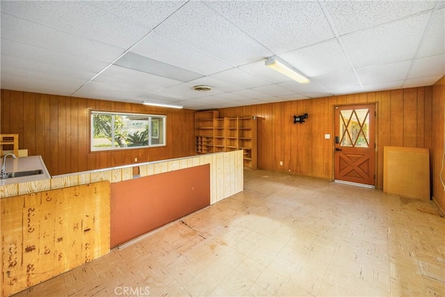 bar featuring tile patterned floors, wood walls, and a sink