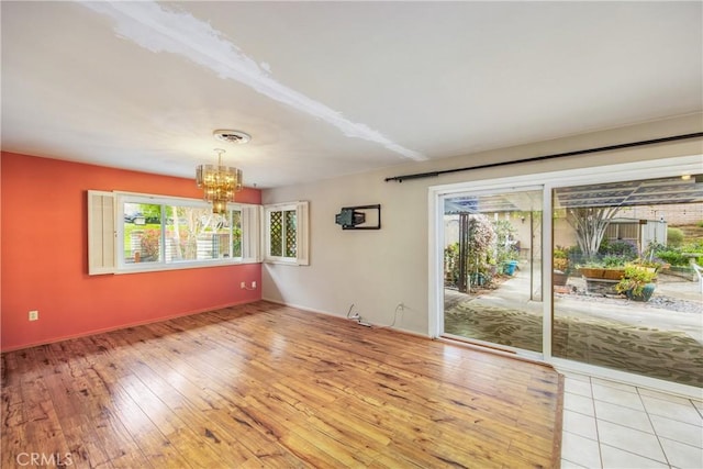 empty room featuring visible vents, light wood-style floors, and a chandelier