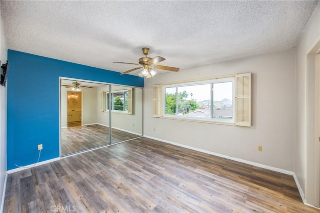 unfurnished bedroom with a closet, baseboards, a textured ceiling, and wood finished floors