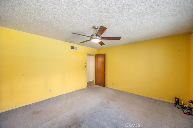 empty room featuring a ceiling fan, visible vents, carpet floors, and a textured ceiling