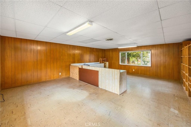 kitchen with tile patterned floors, visible vents, and wood walls