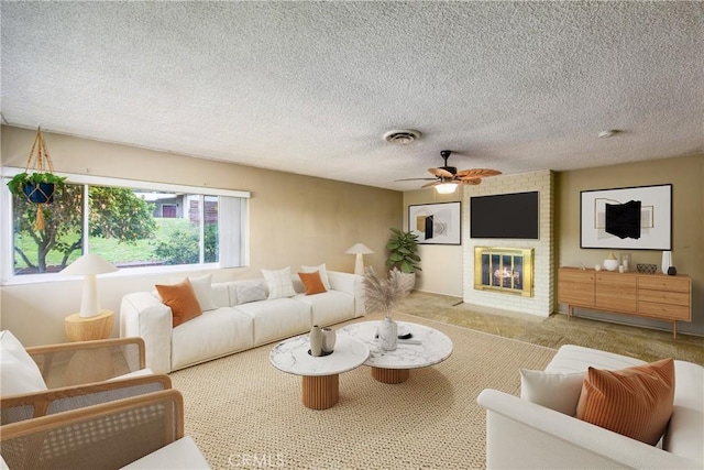 living room with visible vents, a fireplace, ceiling fan, a textured ceiling, and carpet flooring