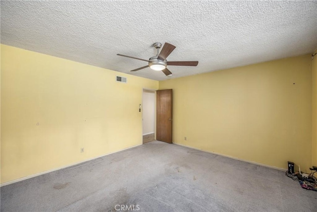 unfurnished room with visible vents, carpet, ceiling fan, and a textured ceiling