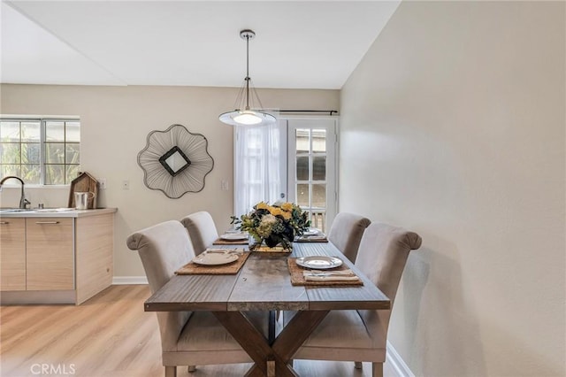 dining space with sink and light wood-type flooring