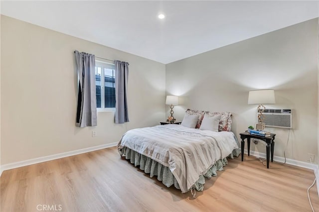 bedroom with a wall unit AC and light wood-type flooring