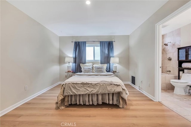 bedroom featuring ensuite bath and light hardwood / wood-style flooring