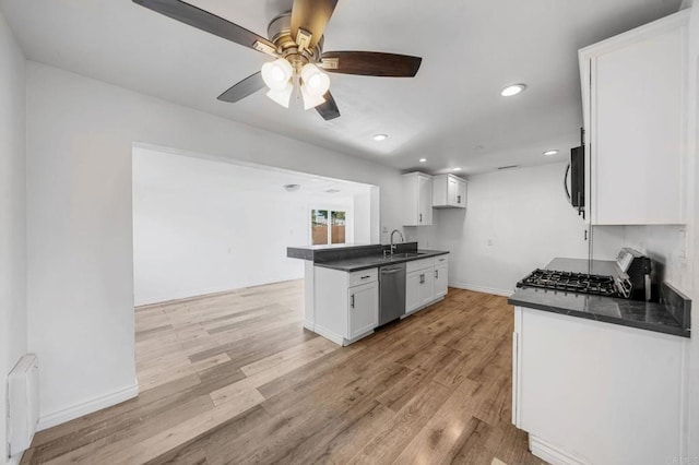 kitchen with radiator heating unit, stainless steel dishwasher, white cabinets, and range