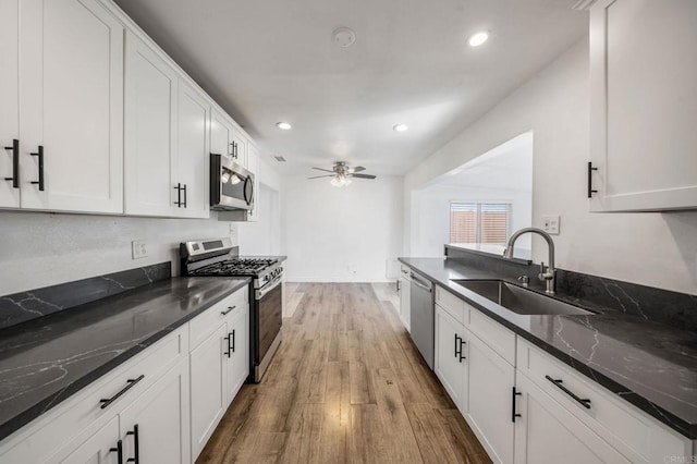 kitchen featuring white cabinetry, stainless steel appliances, sink, and dark stone countertops