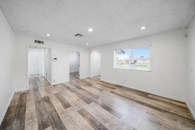 unfurnished room with a textured ceiling and light hardwood / wood-style flooring