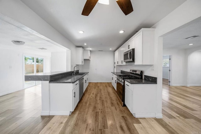 kitchen featuring appliances with stainless steel finishes, sink, white cabinets, kitchen peninsula, and light hardwood / wood-style flooring