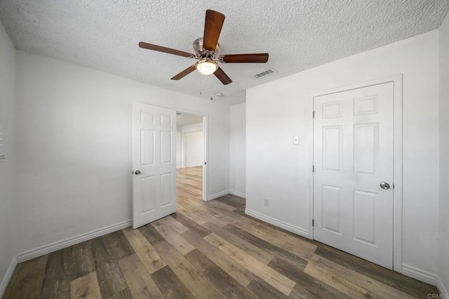 unfurnished bedroom featuring ceiling fan, wood-type flooring, and a textured ceiling