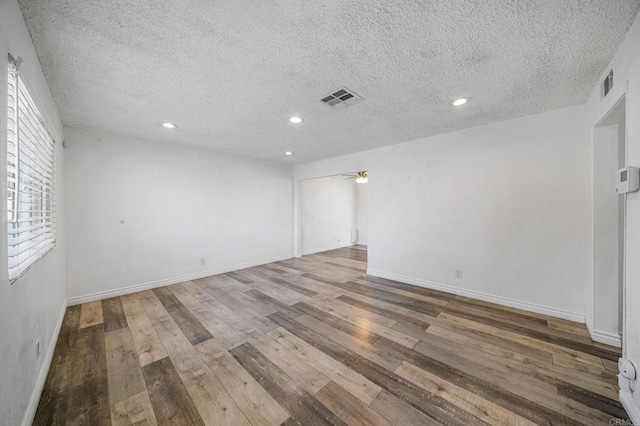 spare room featuring wood-type flooring, a textured ceiling, and ceiling fan