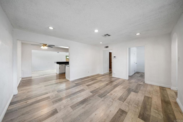 unfurnished living room with ceiling fan, a textured ceiling, and light wood-type flooring