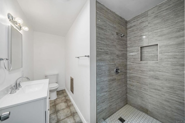 bathroom featuring vanity, toilet, and tiled shower