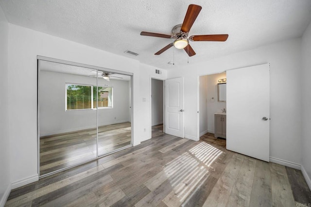 unfurnished bedroom with ceiling fan, light hardwood / wood-style floors, a closet, and a textured ceiling