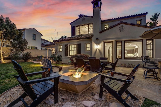 back house at dusk with a patio area and an outdoor fire pit