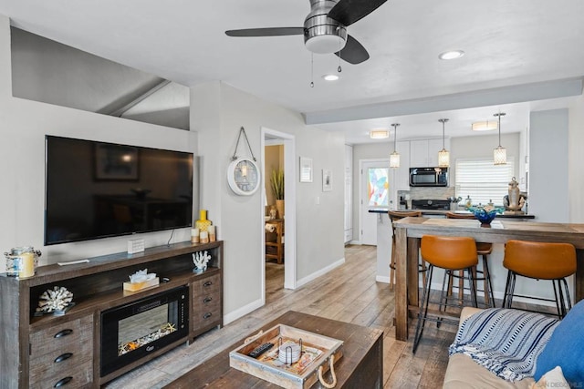 living room with ceiling fan and light hardwood / wood-style flooring