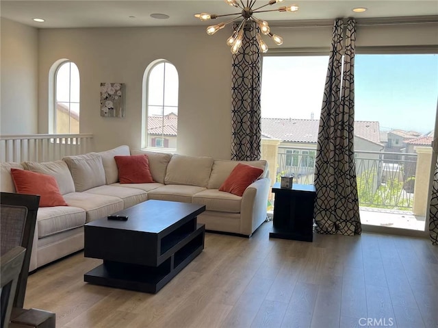 living room with plenty of natural light, an inviting chandelier, and light wood-type flooring