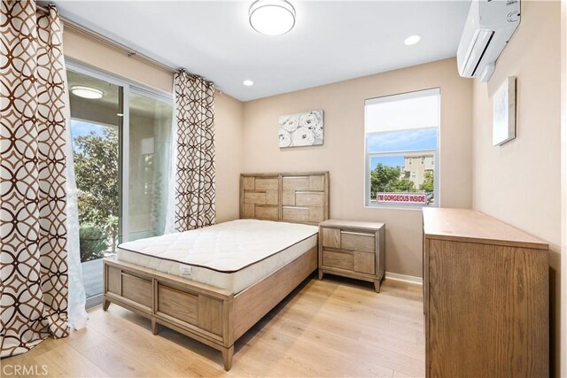 bedroom with access to exterior, a wall unit AC, and light hardwood / wood-style flooring