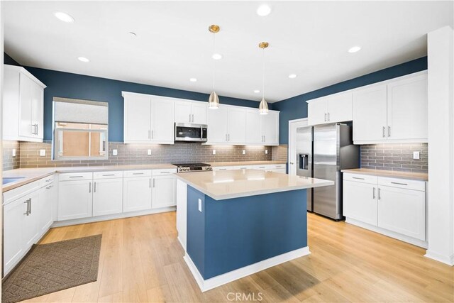 kitchen with white cabinetry, appliances with stainless steel finishes, a center island, and pendant lighting