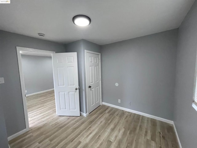 unfurnished bedroom with light wood-type flooring and a closet