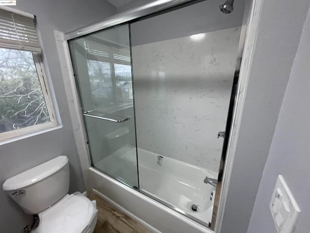 bathroom featuring bath / shower combo with glass door and toilet