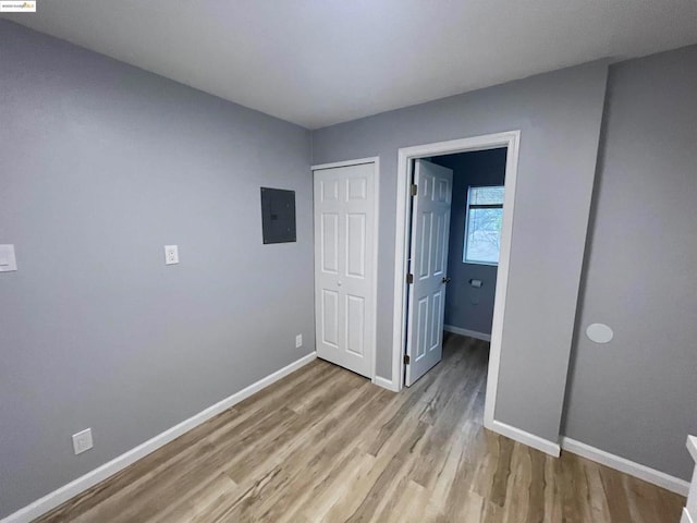 unfurnished bedroom featuring electric panel, a closet, and light wood-type flooring