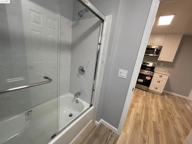 bathroom featuring enclosed tub / shower combo and wood-type flooring