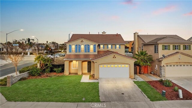 mediterranean / spanish home featuring a front lawn, stucco siding, a tiled roof, and concrete driveway