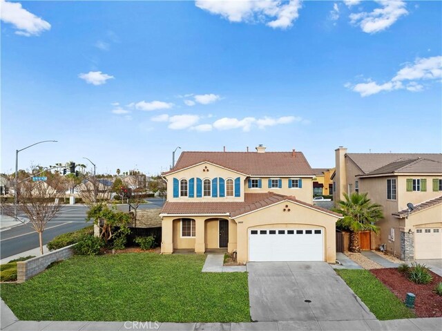 mediterranean / spanish home with a tile roof, a front yard, concrete driveway, an attached garage, and stucco siding