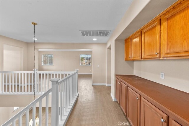 hall featuring visible vents, baseboards, recessed lighting, light wood finished floors, and an upstairs landing