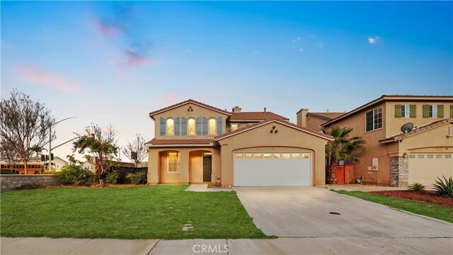 mediterranean / spanish house with driveway, a tile roof, a garage, a front lawn, and stucco siding
