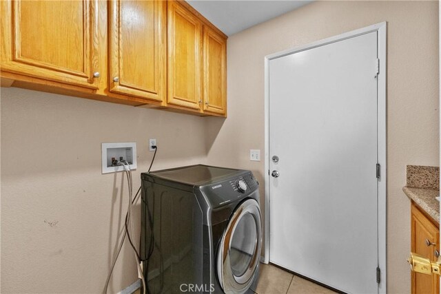 washroom featuring cabinet space, light tile patterned flooring, and washer / clothes dryer