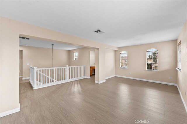 empty room with visible vents, baseboards, and wood finished floors