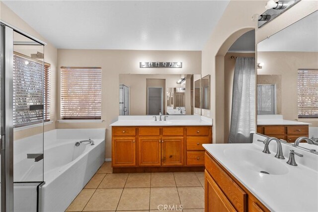 full bath featuring a garden tub, a sink, tile patterned floors, and two vanities