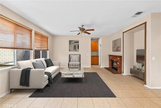 living area with ceiling fan, a fireplace, baseboards, light tile patterned floors, and visible vents